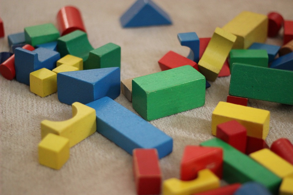 Coloured, wooden building blocks scattered on a carpeted floor