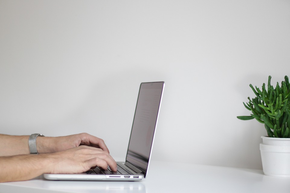 Hands typing on a laptop keyboard