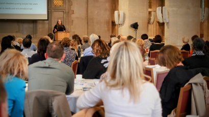 A group of colleagues sit listening to a speaker at a conference